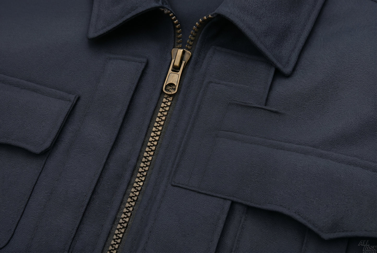 Close-up detail of the CAL FIRE Flying Cross duty jacket chest area — heavy-duty charcoal-gray metal-tooth zipper with pull, zipper placket, and chest pocket flaps visible against the midnight-navy twill.