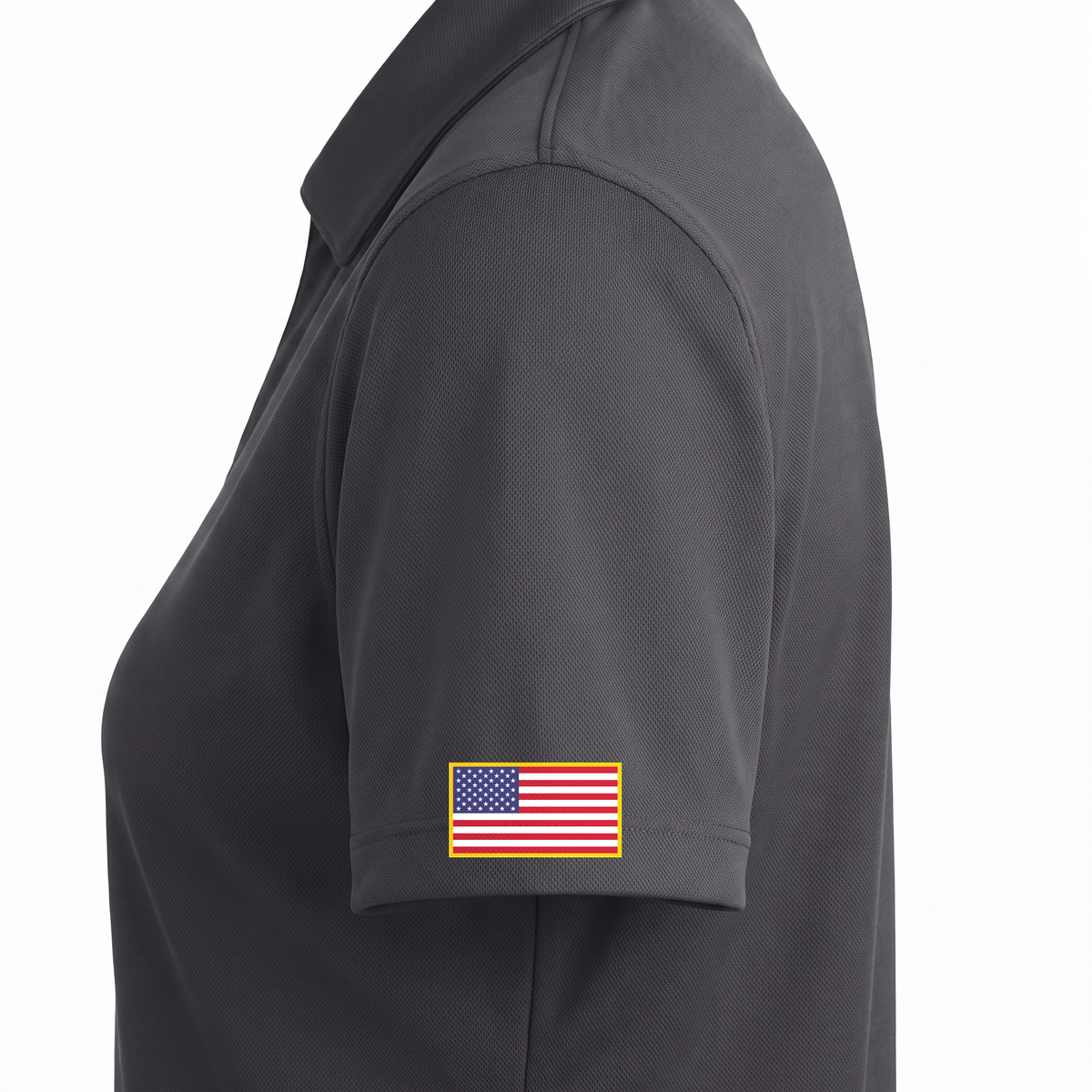 Siskiyou Trojans ladies Sport-Tek polo in iron grey, close-up of the left sleeve showing the United States flag patch just above the sleeve hem