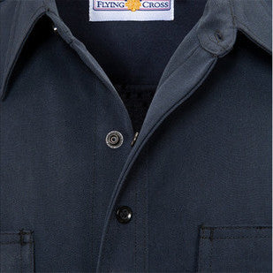 Close-up of the navy wool shirt's collar and front placket showing the woven Flying Cross neck label and dark snap buttons.