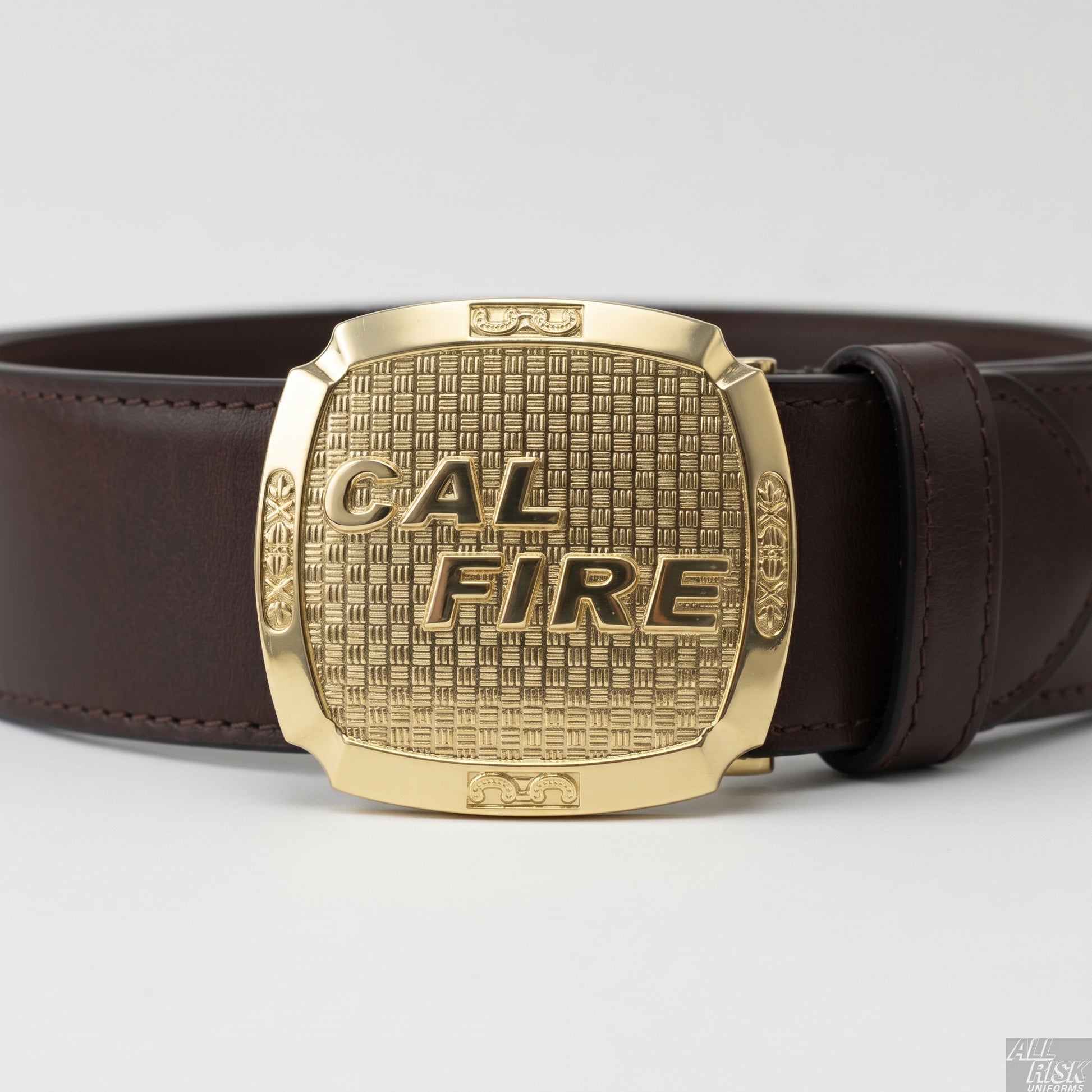 CAL FIRE gold-brass belt buckle worn on a brown saddle-leather belt — close-up showing the buckle attached to the belt strap, raised CAL FIRE lettering and basket-weave field clearly visible.
