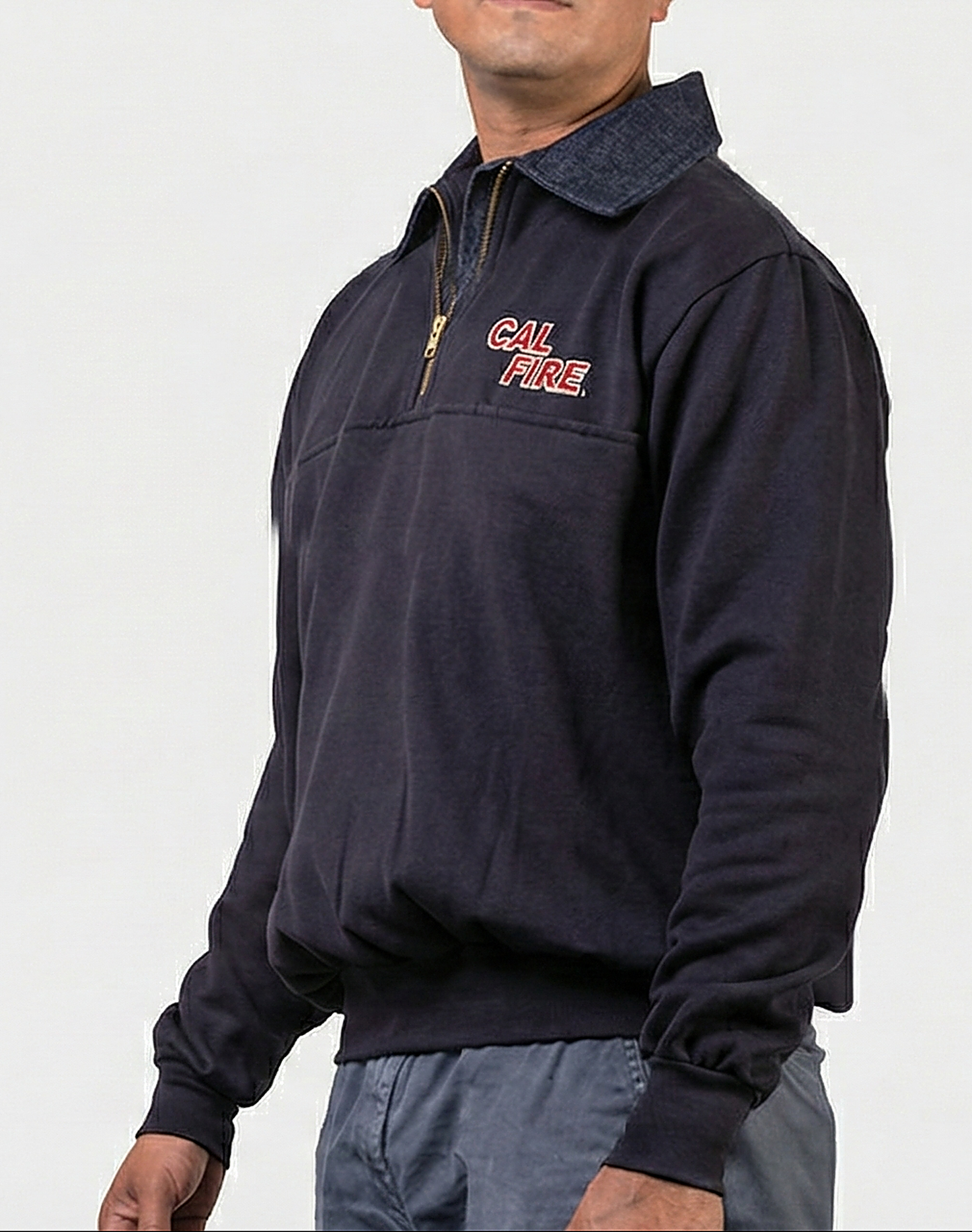 Side profile of a model in the navy job shirt, red CAL FIRE italic wordmark on the chest with the denim collar and gold quarter-zip.