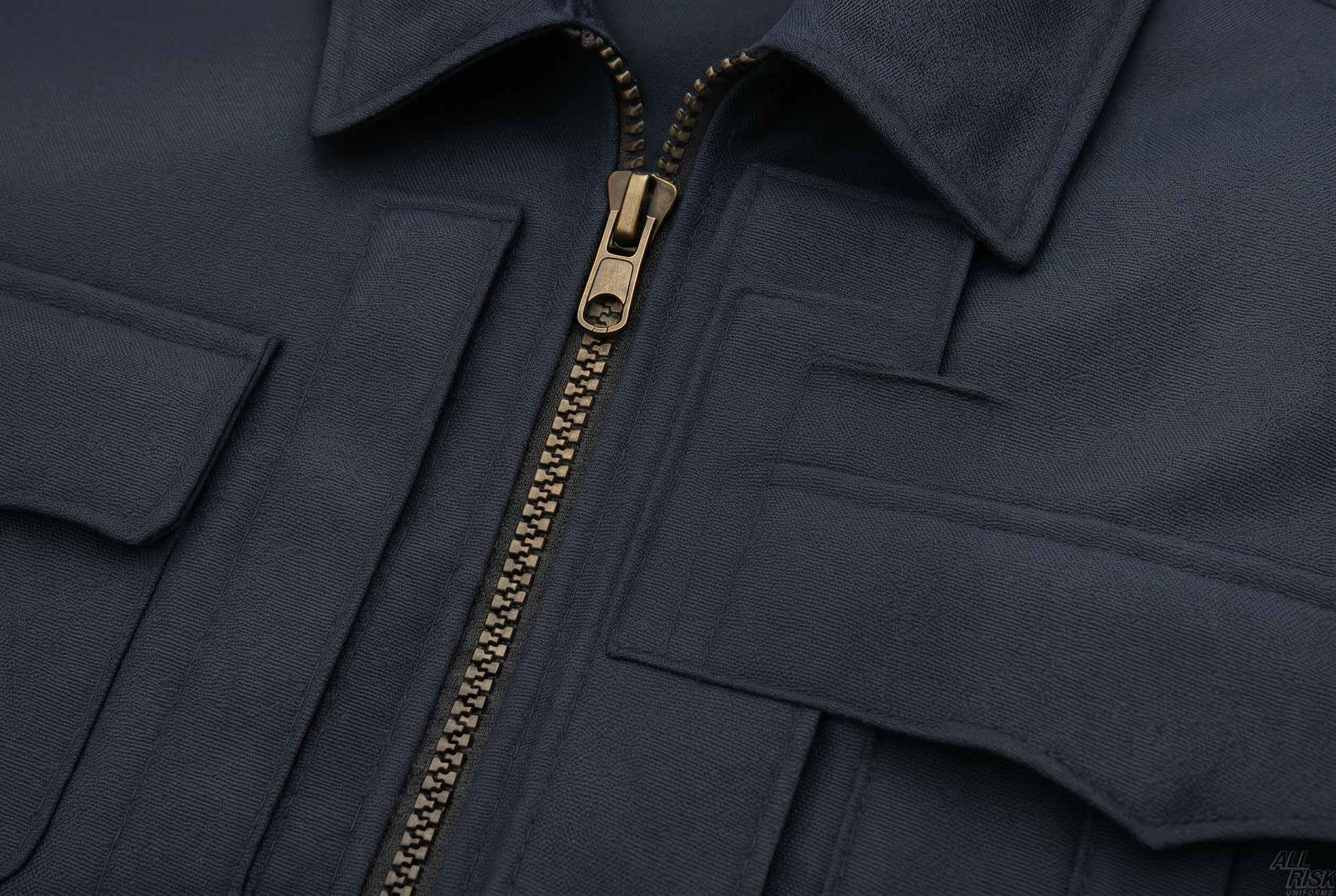 Close-up detail of the CAL FIRE Flying Cross duty jacket chest area — heavy-duty charcoal-gray metal-tooth zipper with pull, zipper placket, and chest pocket flaps visible against the midnight-navy twill.