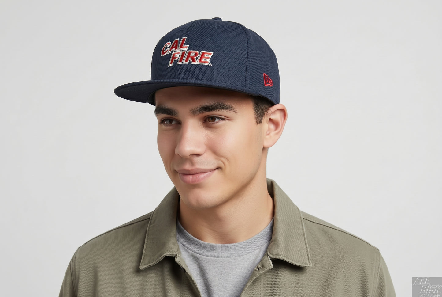Model close-up of a man in an olive overshirt wearing the navy snapback with the red CAL FIRE wordmark and the New Era flag on the side.