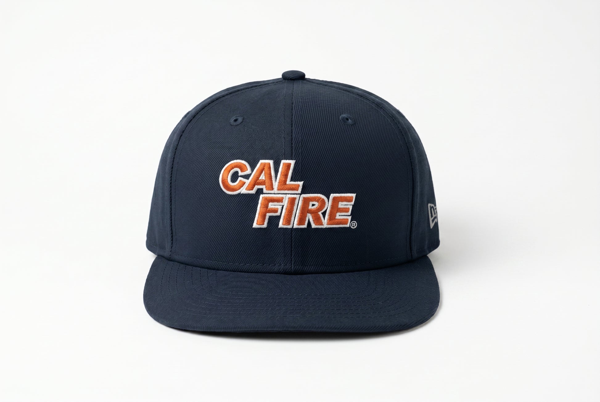 Straight-on front view of the navy snapback showing the orange-red CAL FIRE wordmark centered on the crown and a tonal New Era flag on the side.