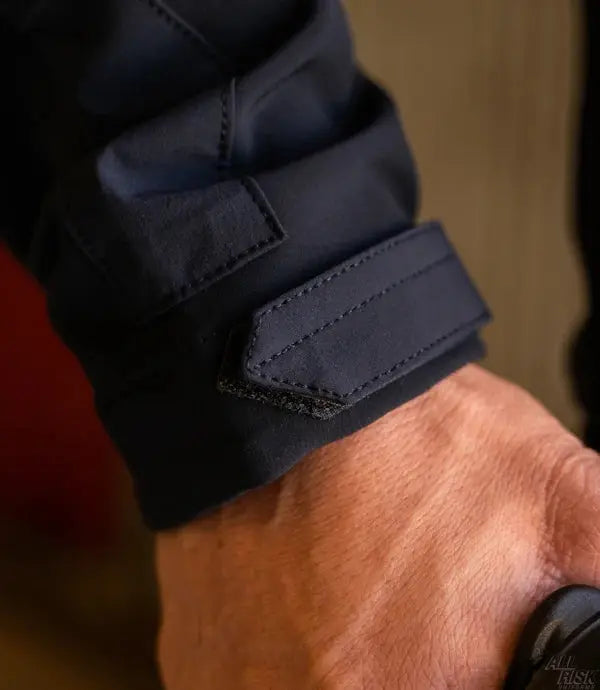 Close-up of a person's wrist wearing a navy blue sleeve with a blurred background