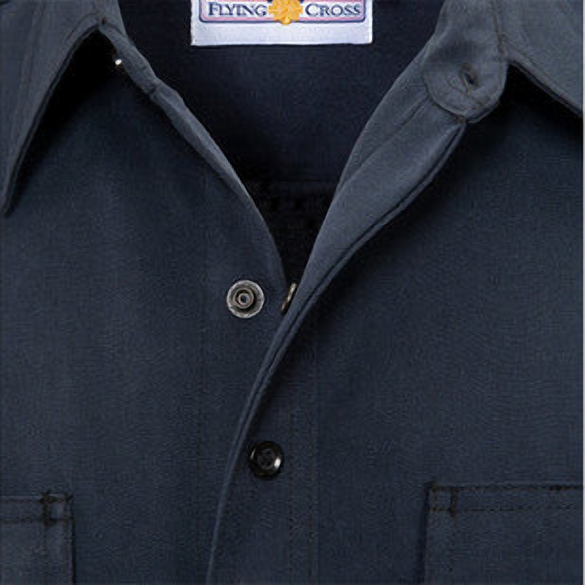 Close-up of the navy wool shirt's collar and front placket showing the woven Flying Cross neck label and dark snap buttons.