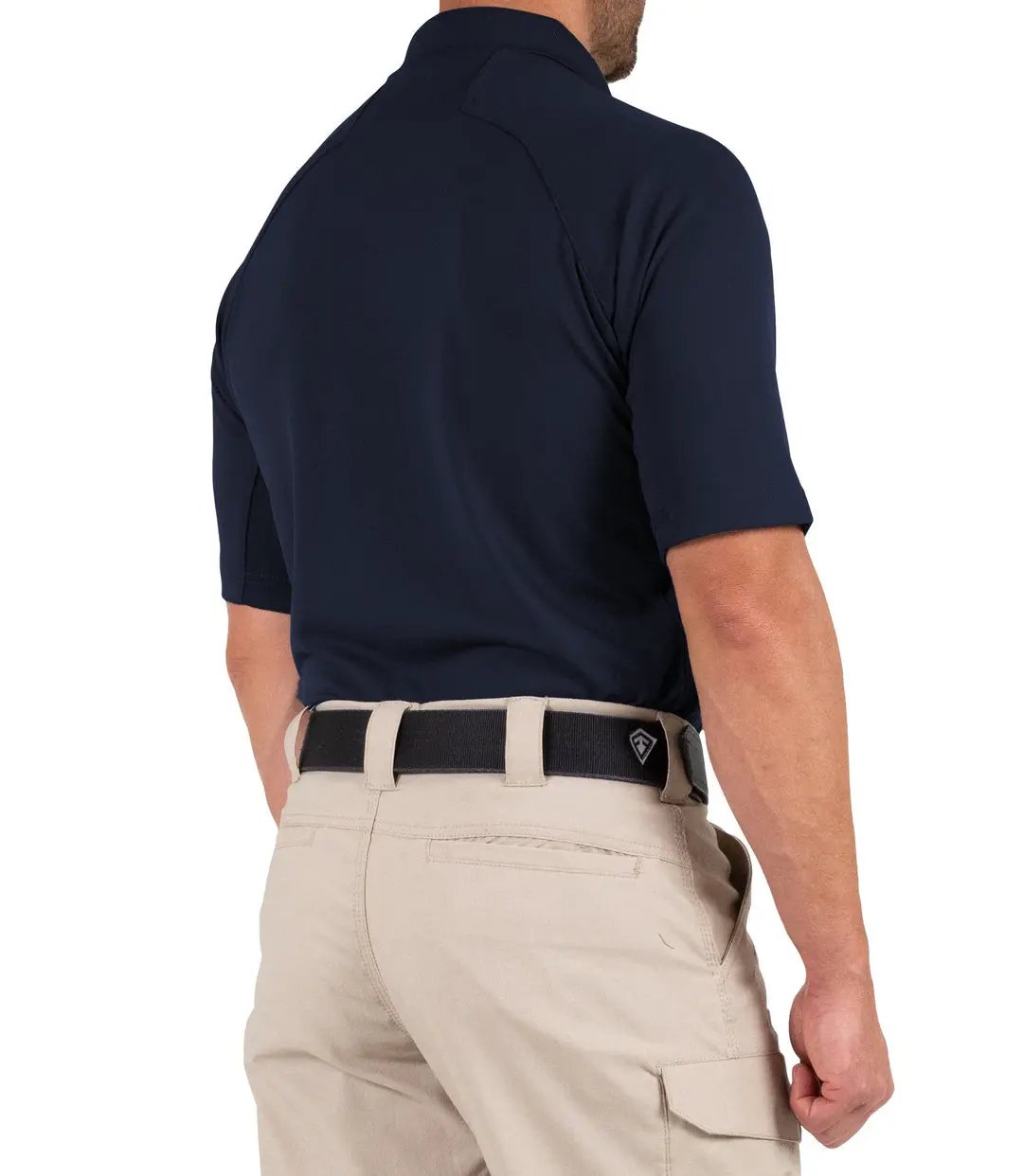 Rear three-quarter view of a model in the navy polo and khaki tactical pants, with a First Tactical logo belt buckle at the waist.