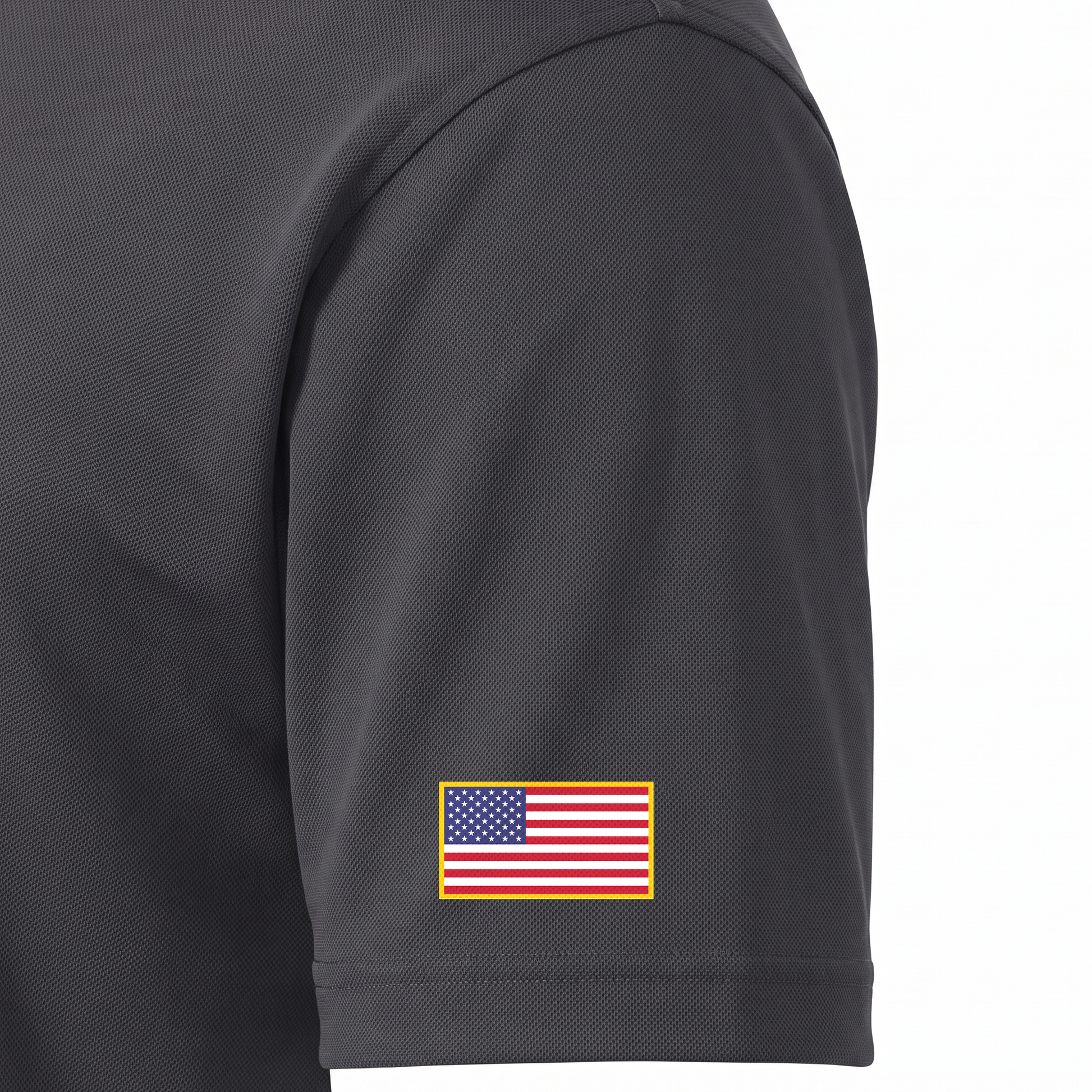 Siskiyou Trojans men's Sport-Tek polo in iron grey, close-up of the left sleeve showing the United States flag patch just above the sleeve hem